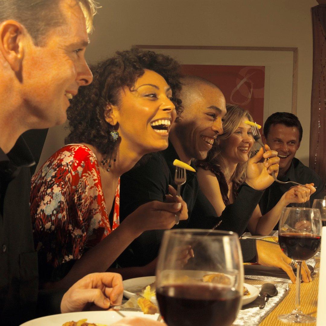 Group of friends enjoying a vegan dinner with wine, sharing laughter and a memorable dining experience.